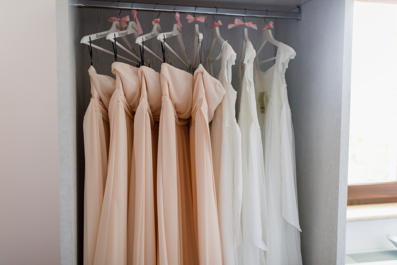Bridesmaids dresses hanging on hangers.